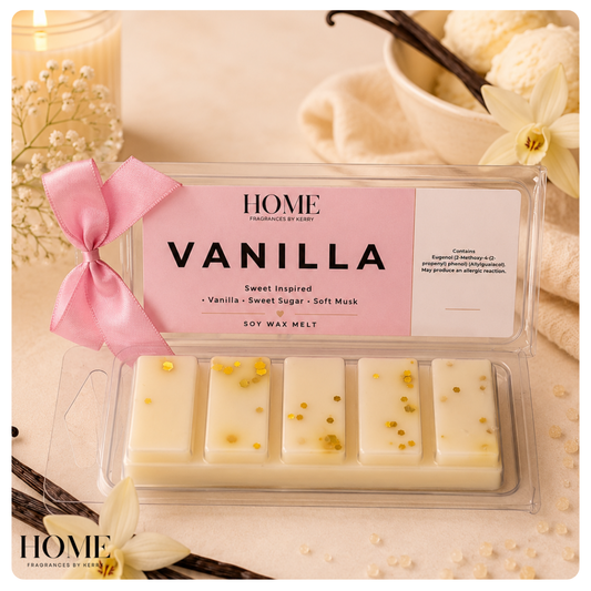 A clear plastic clamshell package of A vanilla-flavored soy wax melts,  with a pink ribbon, shown on a warm cream surface with candles, flowers, and vanilla beans in the background. The label reads HOME FRAGRANCES BY KERRY