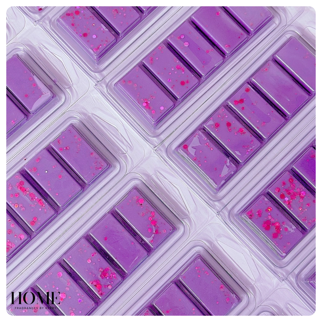 Purple wax melt bar with pink specks on a white background